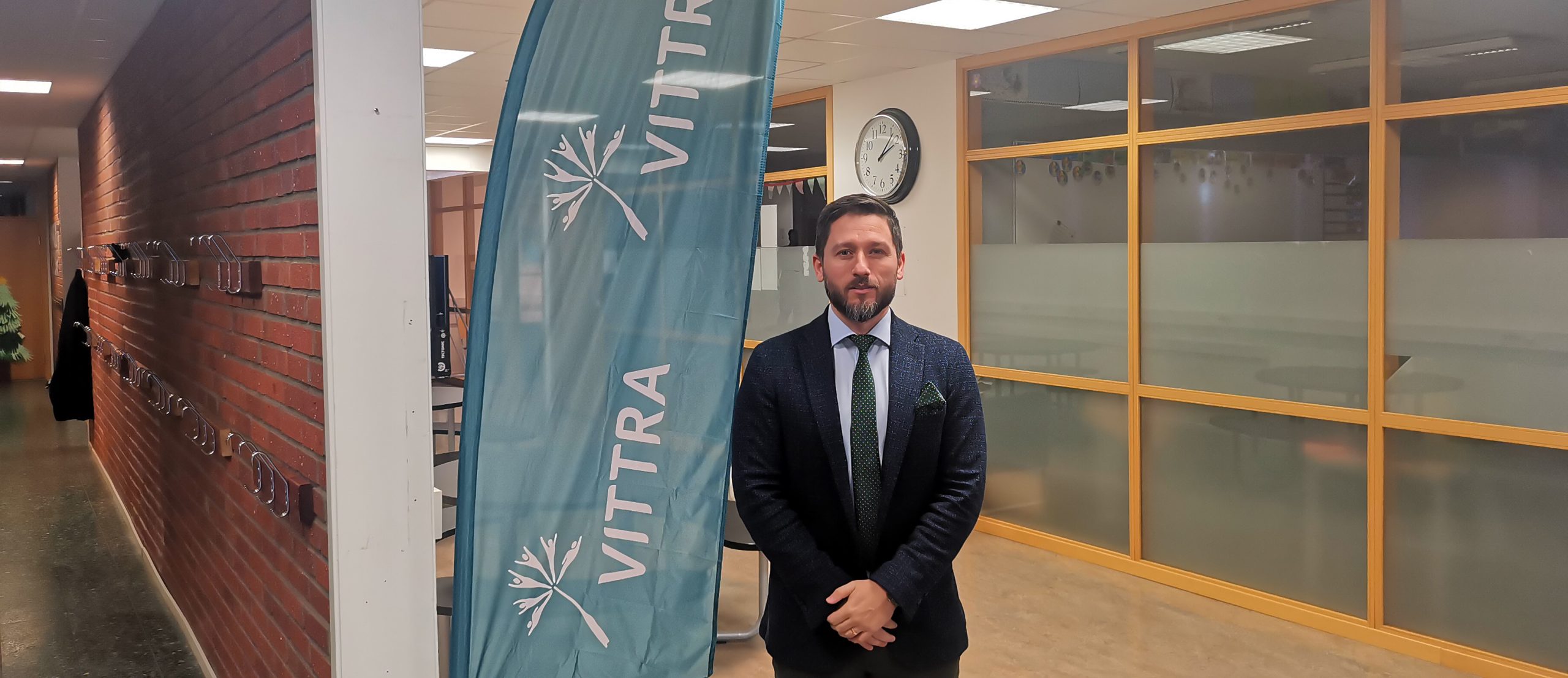 Vittra Gävles rektor står bredvid en Vittra-flagga i skolan.