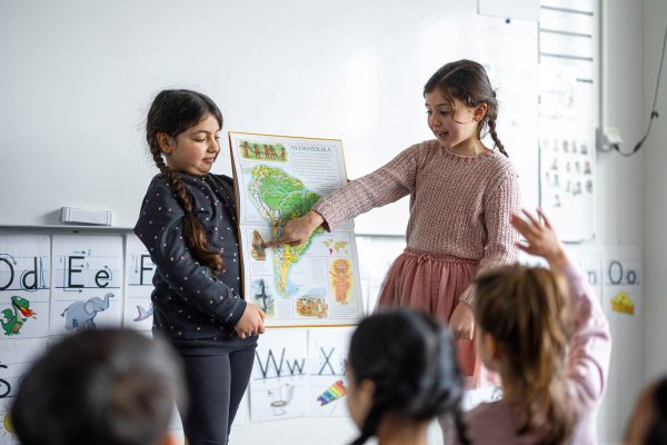 Två elever i förskolan visar en karta över Sydamerika för klassen.