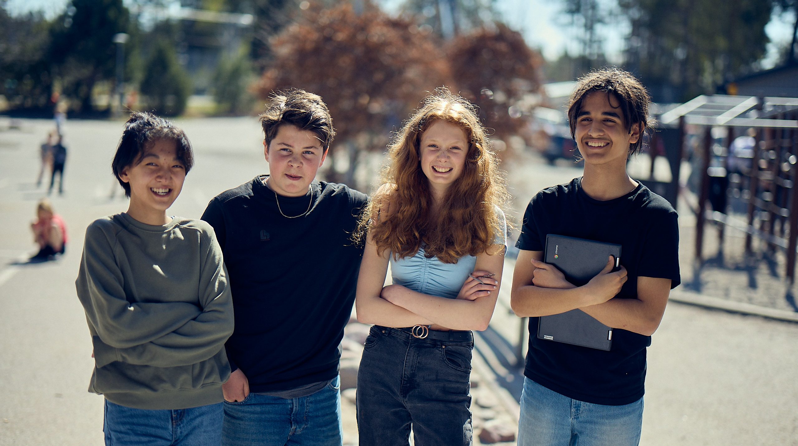 Fyra elever står på skolgården en solig dag