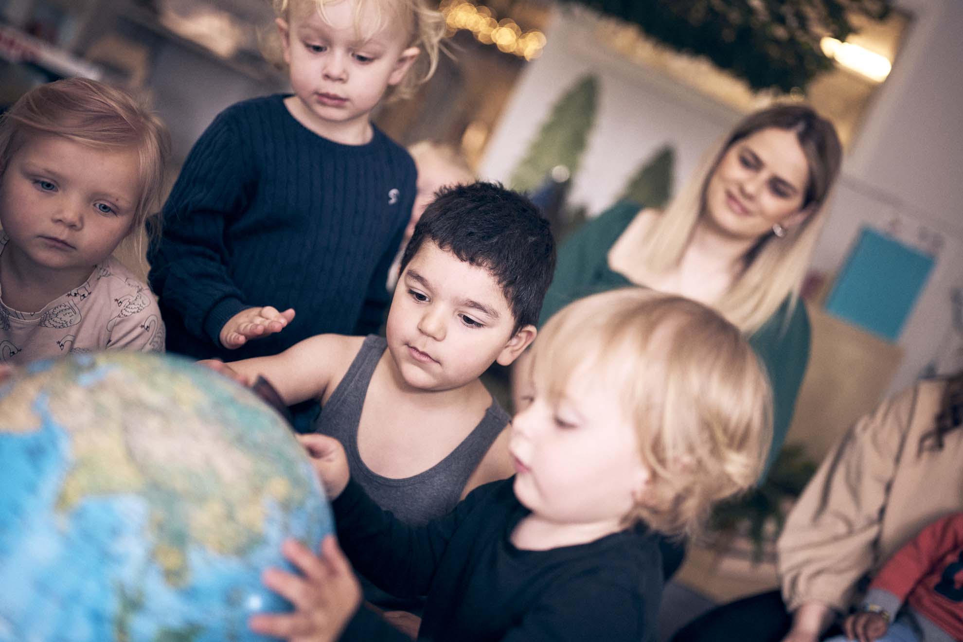 Fyra barn på en förskola på Vittra sitter och tittar på en jordglob tillsammans.