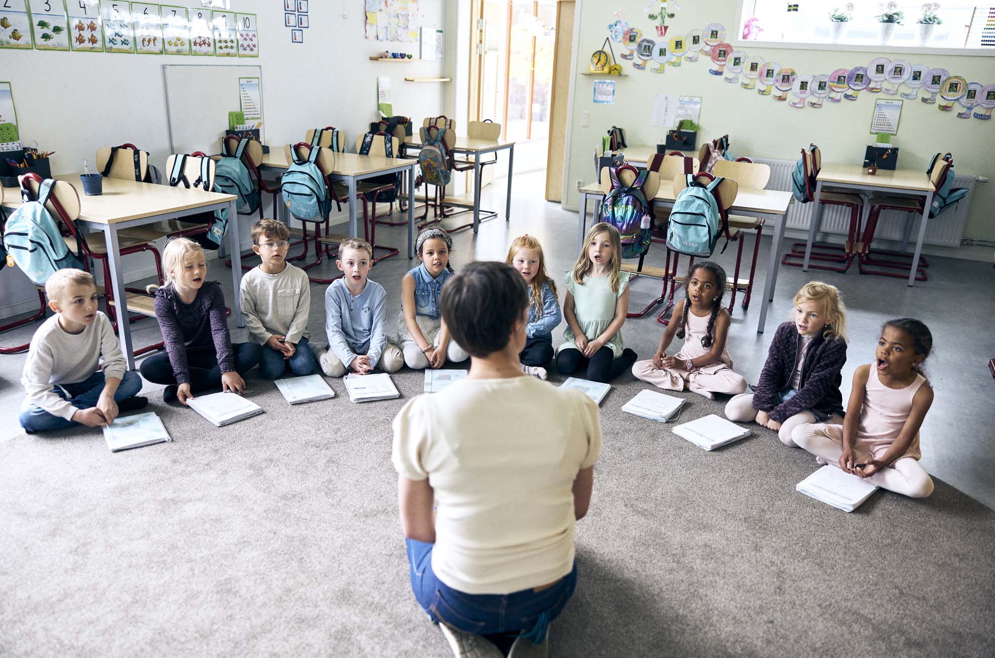 Elever sitter i en halvcirkel med sina Vittraböcker framför en pedagog