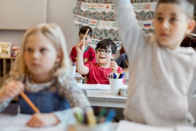 Elever räcker upp händerna i klassrummet.