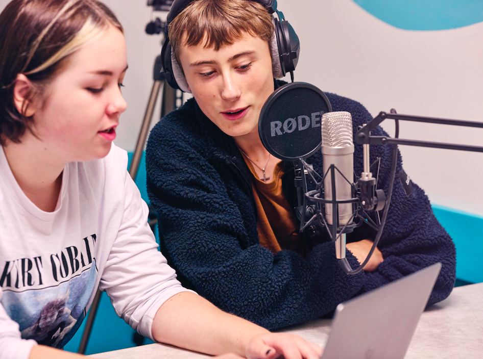 Elever med dator och ljudutrustning som spelar in på en redaktion för ett samhällsengagerat lärande
