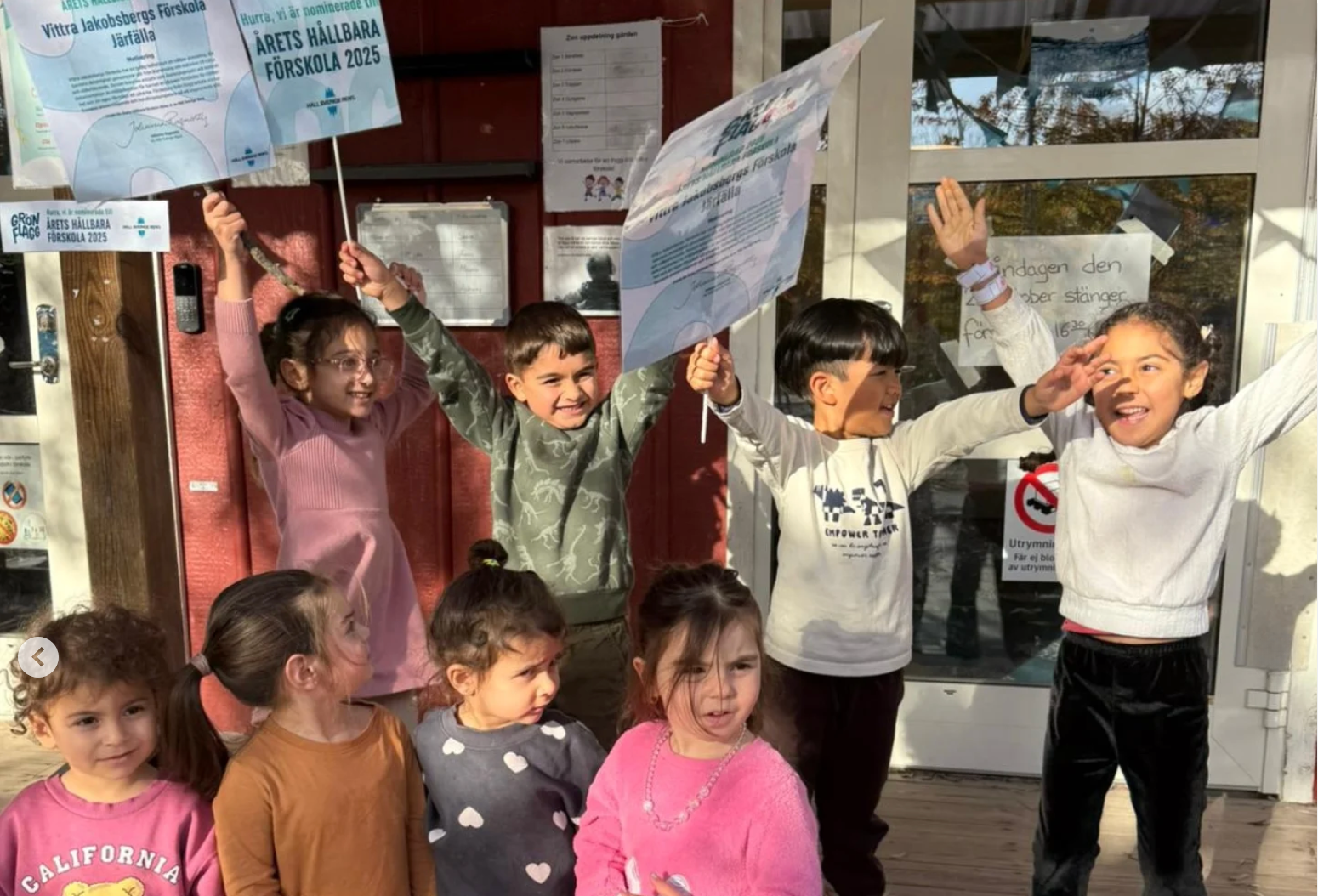 Elever står med skyltar där det står: Årets hållbara förskola. De sträcker upp händerna och ser glada ut.