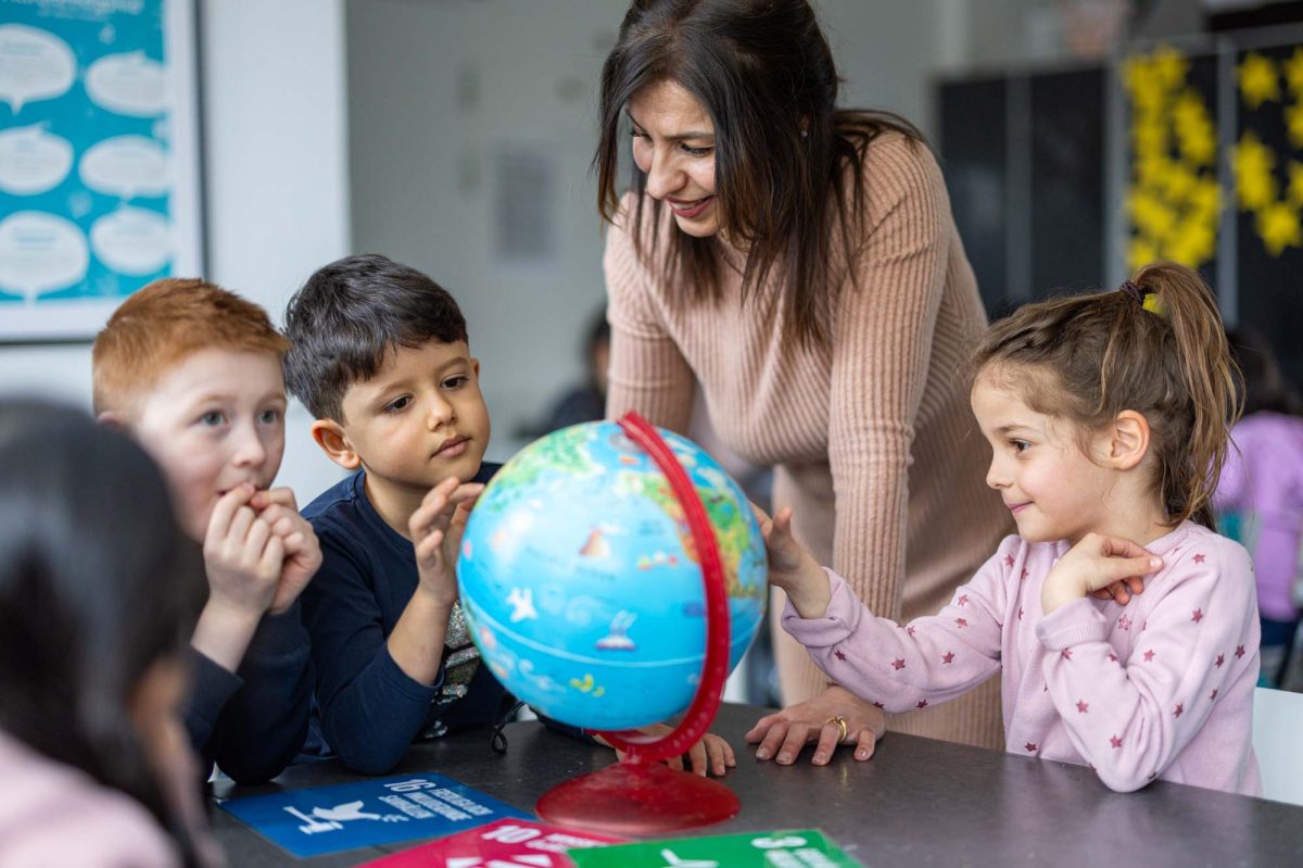 Tre elever och en lärare tittar på en jordglob