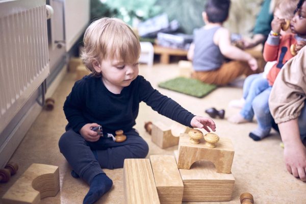 Ett barn på Vittras förskola sitter på golvet och leker med träklossar.