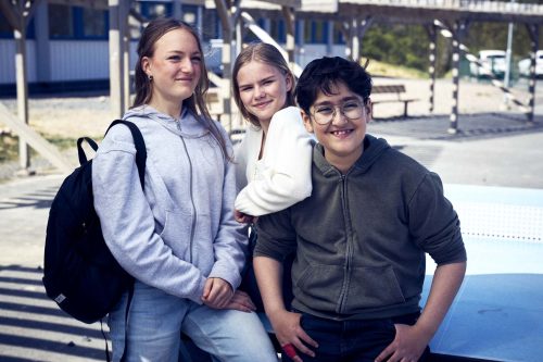 Tre högstadieelever umgås vid ett pingisbord ute på skolgården