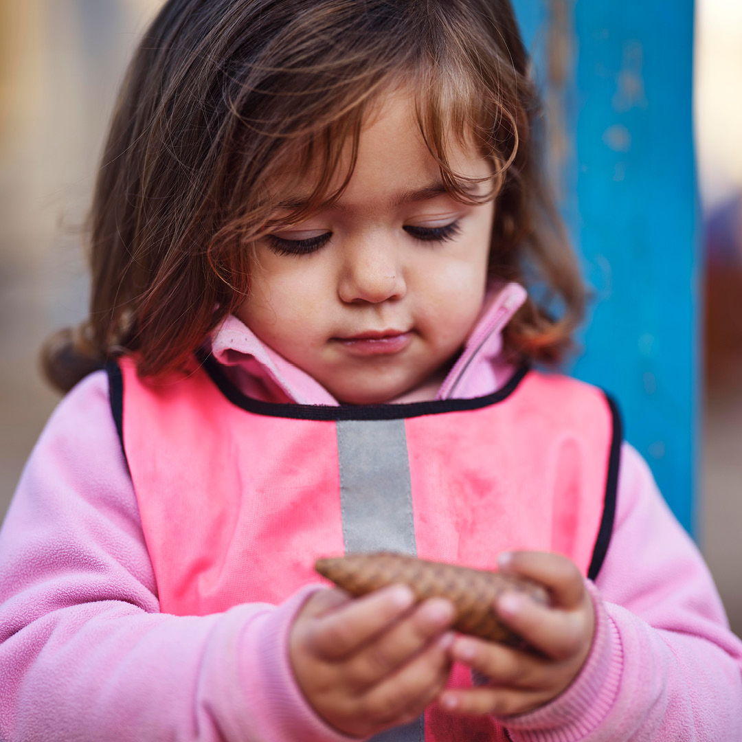 Flicka på förskolan med kotte i handen vid lärande utomhus