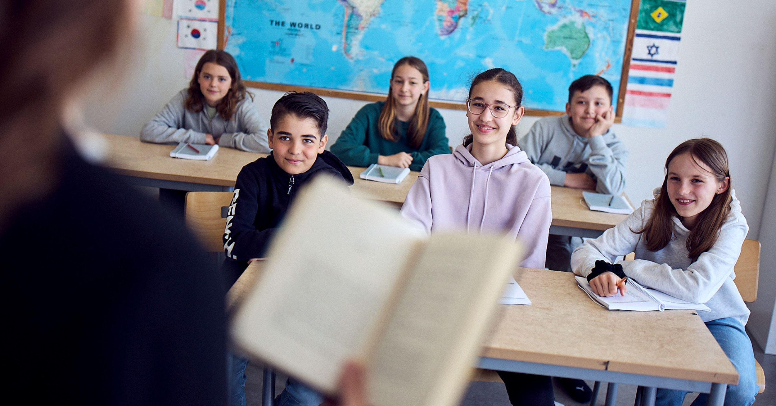 Elever i klassrum på Vittra lyssnar till lärare som läser högt ur en bok