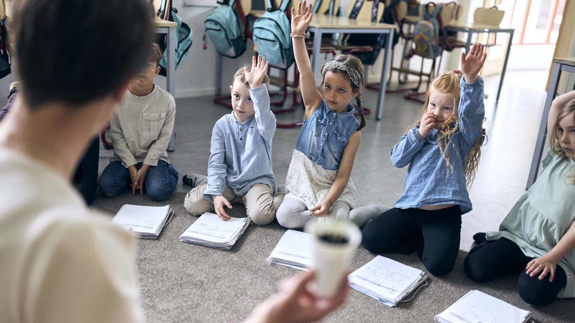 En förskoleklass på Vittra Vallentuna sitter i en ring på golvet och lyssnar på läraren.
