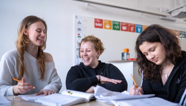 Två högstadieelever på Vittra Örebro får hjälp av en lärare under en lektion.