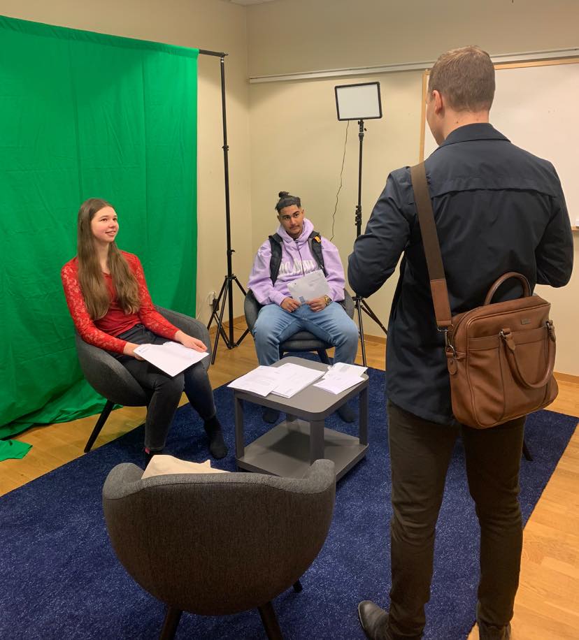 Reporter som intervjuar två elever i inomhusmiljö