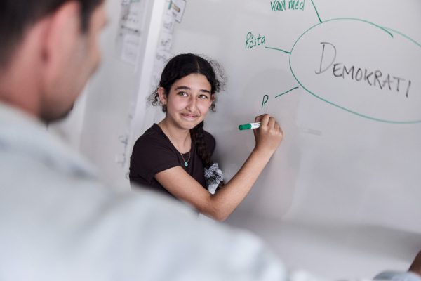 Elev skriver på tavlan i klassrum