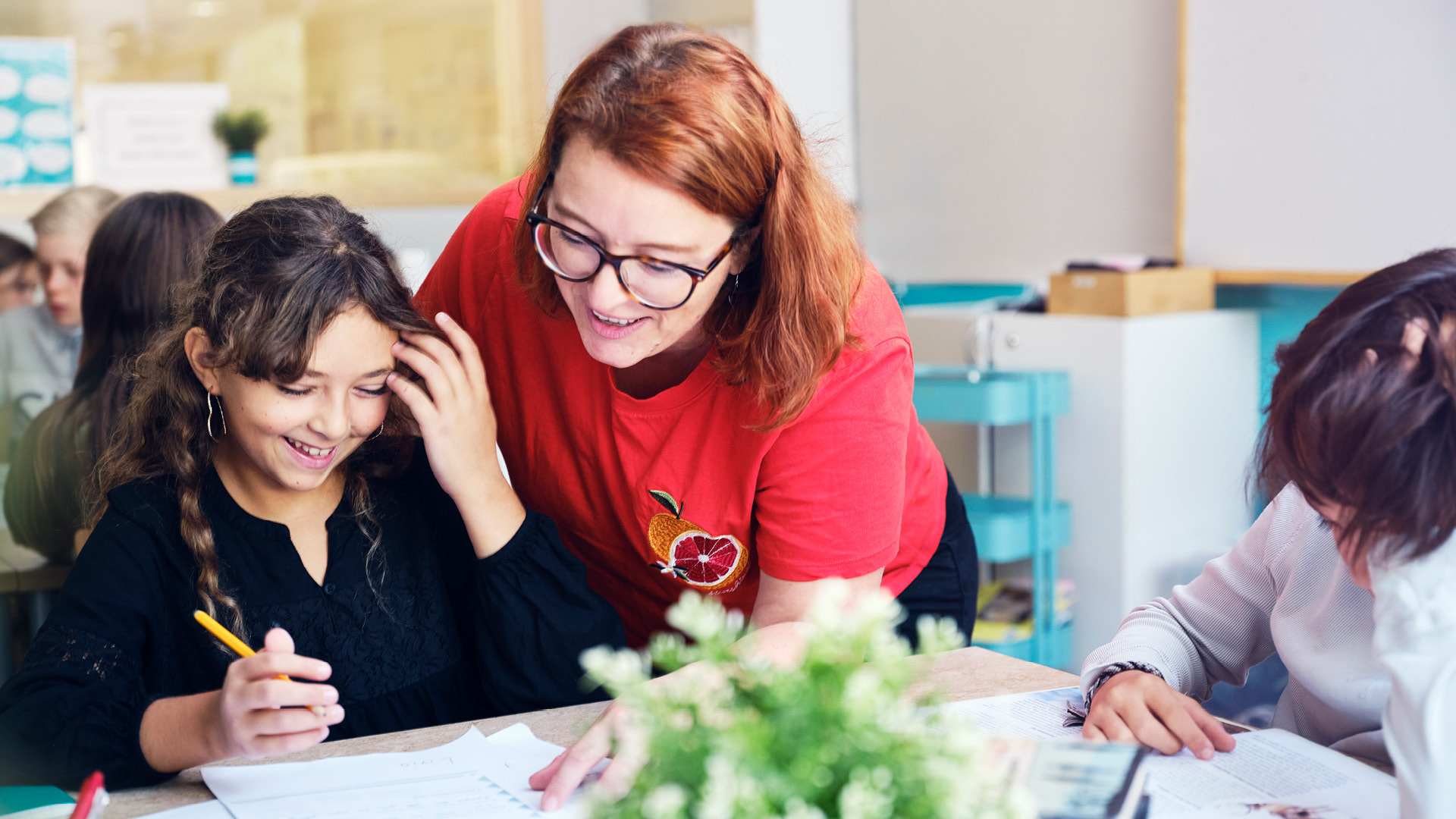 Engagerad lärare som hjälper en elev i ljust klassrum på Vittra Frösunda i Solna
